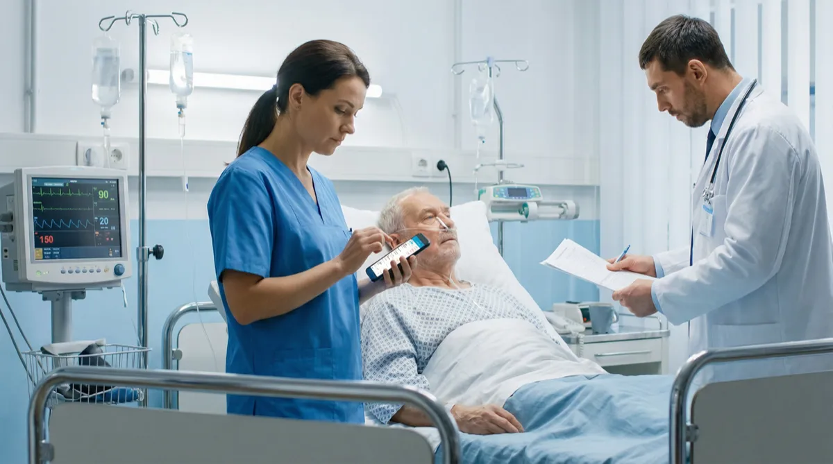Nurse reviewing patient vitals with doctor at bedside